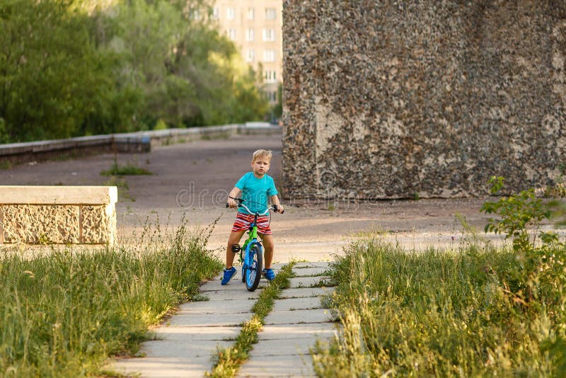 Serious seven-year-old boy riding a bike in the city Park in the summer