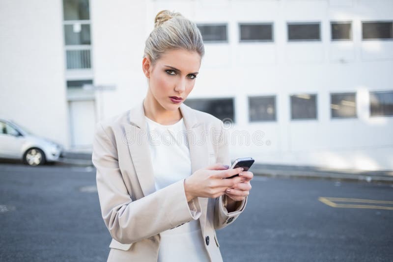 Serious stylish businesswoman sending a text