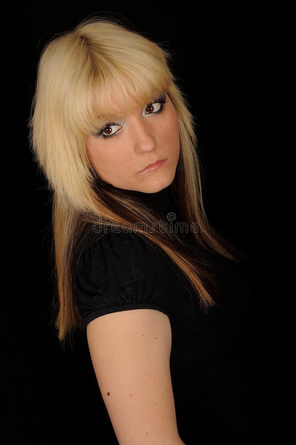 Serious young blond woman wearing black, looking back over her right shoulder in profile. Isolated against a black background. Woman doubtful looking stock images, royalty-free photos and pictures