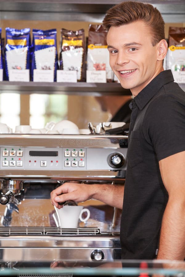 Serious young barista behind counter. stock photos