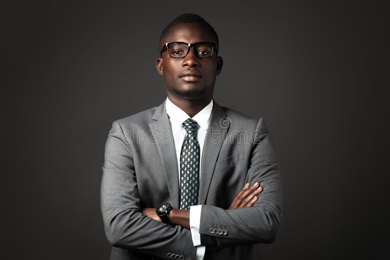 Serious young black man with glasses and gray business suit crossed his arms