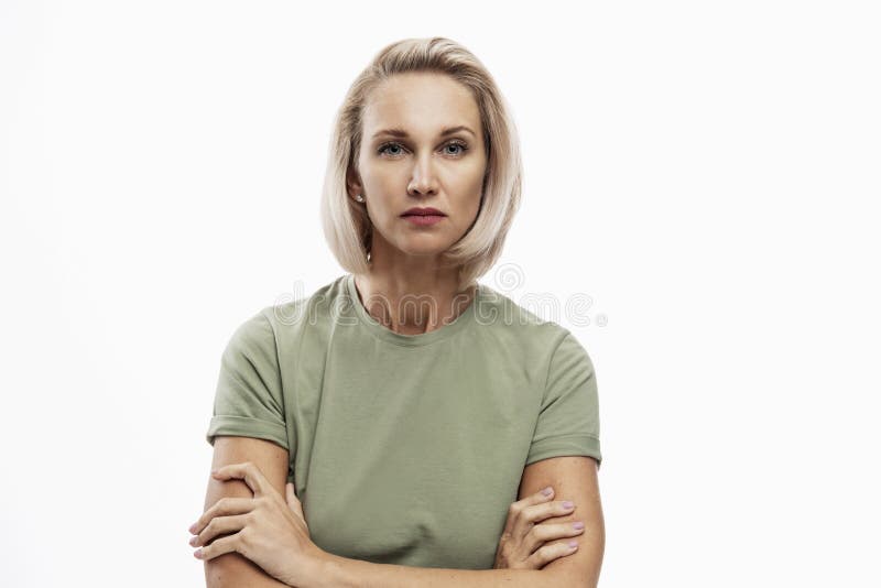 Serious young blonde woman with arms crossed on her chest looks strictly into the camera. Isolated on white background