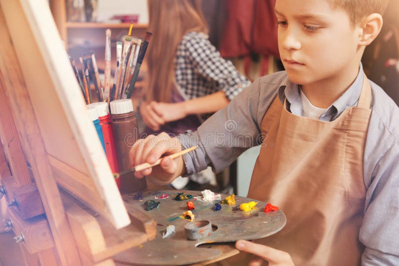 Serious young boy painting on art canvas royalty free stock photos Serious young boy painting on art canvas royalty free stock photos