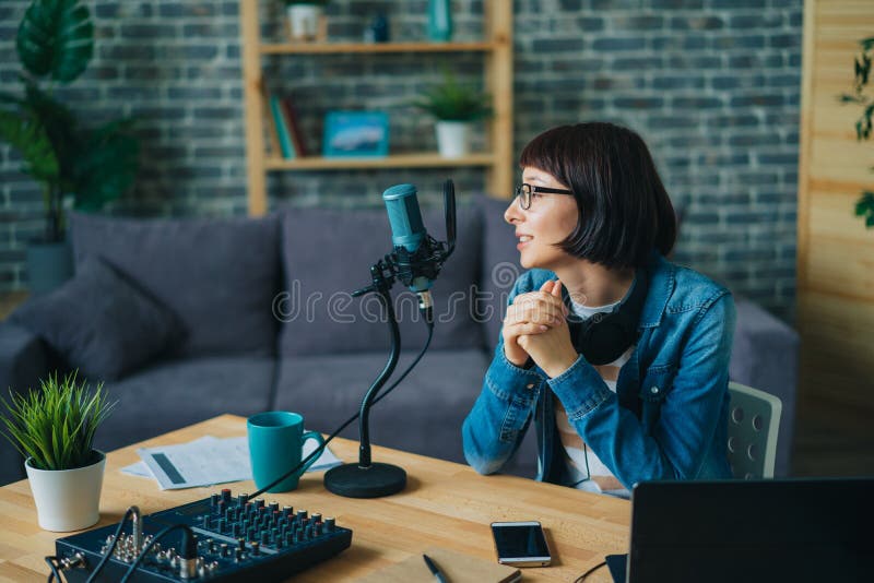 Serious woman in glasses speaking in microphone recording speech for audio blog stock photo Serious woman in glasses speaking in microphone recording speech for audio blog stock photo