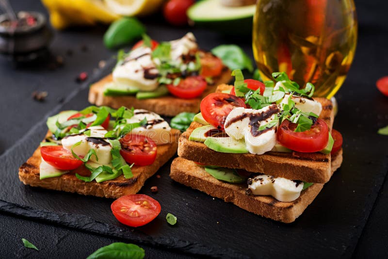 Serrez les pains grillés avec les tomates, le mozzarella, l'avocat et le basilic photos libres de droits Serrez les pains grillés avec les tomates, le mozzarella, l'avocat et le basilic photos libres de droits