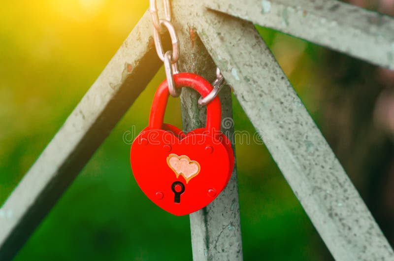 Serrure fermée de mariage rouge sous forme de coeur Le château pèse dedans à un pont sur un fond de ciel bleu un jour ensoleillé images stock Serrure fermée de mariage rouge sous forme de coeur Le château pèse dedans à un pont sur un fond de ciel bleu un jour ensoleillé images stock