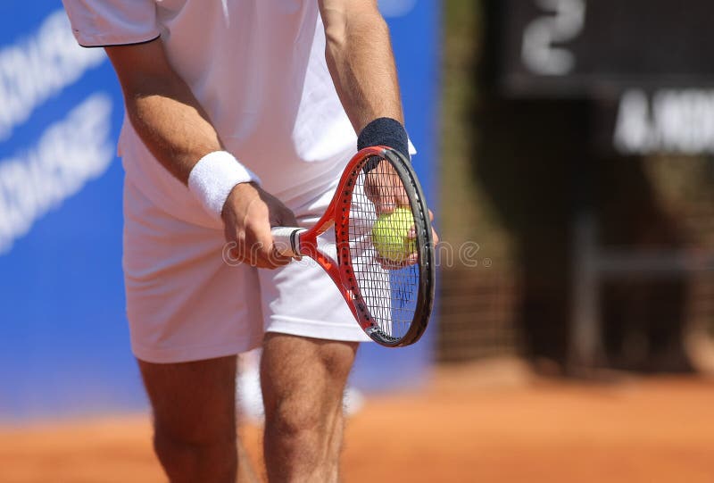 A tennis player prepares to serve a tennis ball during a match. A tennis player prepares to serve a tennis ball during a match