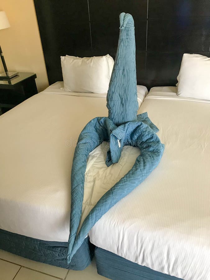 Service d'étage dans une chambre avec des lits rétractés et un chiffre de coeur et un cygne fait de couvertures, couvre-lits des photographie stock Service d'étage dans une chambre avec des lits rétractés et un chiffre de coeur et un cygne fait de couvertures, couvre-lits des photographie stock
