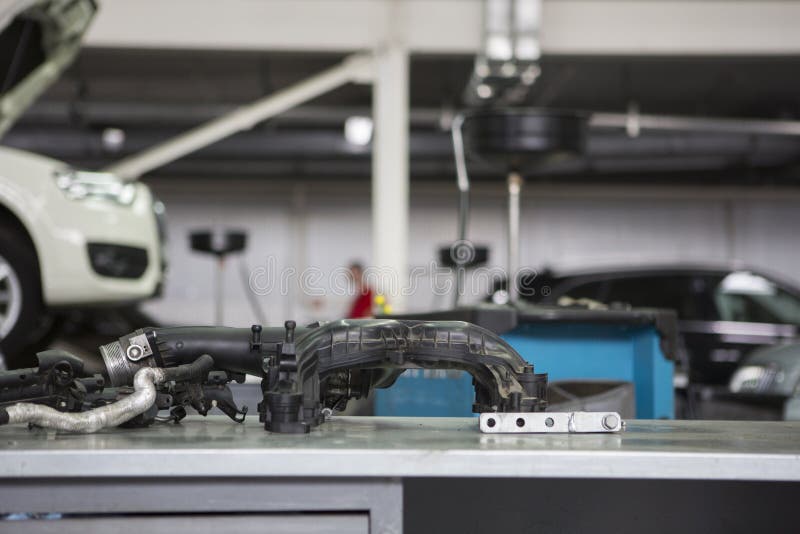 Service de voiture dans les pièces de moteur de premier plan sur la table, sur les voitures troubles d'un fond sur les remonte-pe photographie stock libre de droits Service de voiture dans les pièces de moteur de premier plan sur la table, sur les voitures troubles d'un fond sur les remonte-pe photographie stock libre de droits