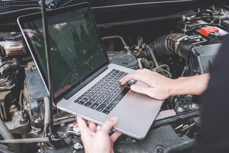 Services car engine machine concept, Automobile mechanic repairman checking a car engine with using computer diagnostics while repairing, car service and maintenance