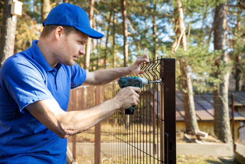 Servicii de scrimă care instalează garduri cu ochiuri metalice sudate stock photos