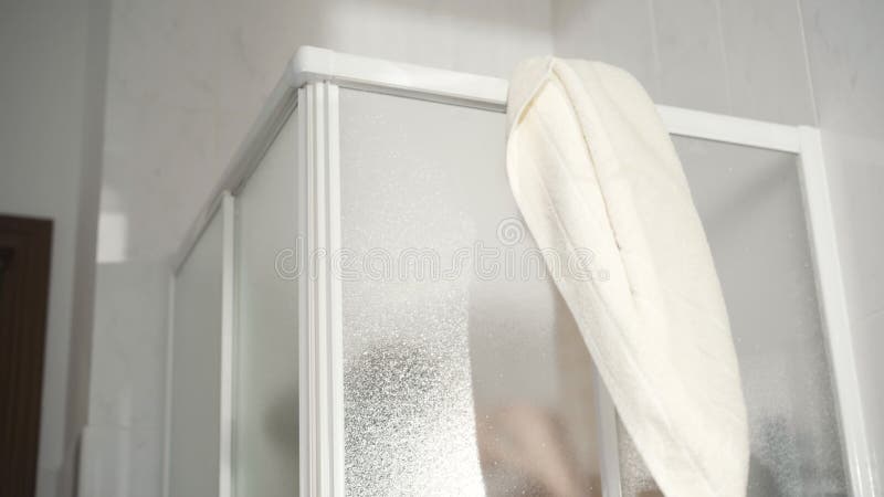 Serviette de pendaison de femme méconnaissable sur la cabine de douche. Dame sous la douche dans la salle de bains à la maison dem