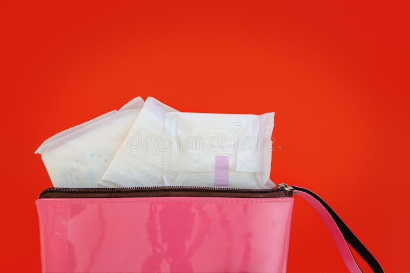 Servilleta sanitaria en bolso del rosa del ` s de las mujeres en fondo rojo fotos de archivo libres de regalías Servilleta sanitaria en bolso del rosa del ` s de las mujeres en fondo rojo fotos de archivo libres de regalías