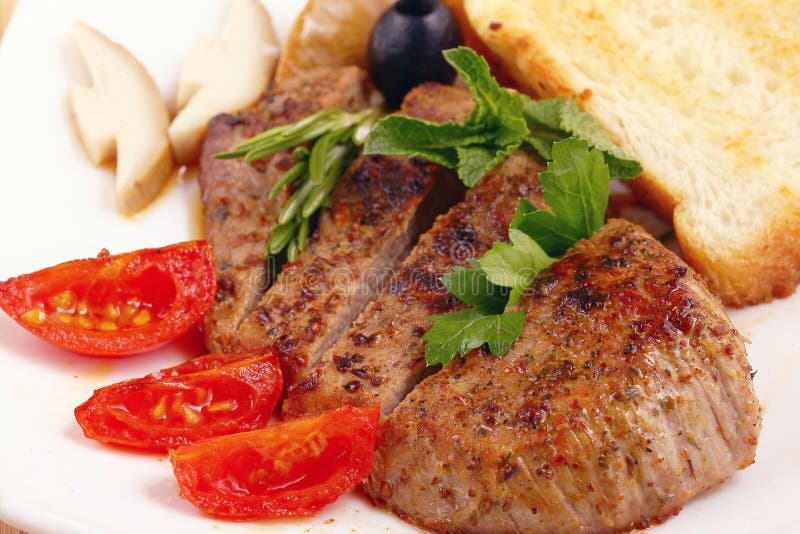 Serving of meat with vegetables on a plate of white background