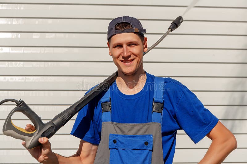 Servizio eliminante del lavoratore in berretto da baseball e camici Lavare le case e le facciate immagini stock Servizio eliminante del lavoratore in berretto da baseball e camici Lavare le case e le facciate immagini stock