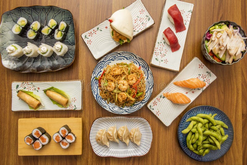 set of asian food dishes with sushi, avocado maki, shrimp noodles, edamame