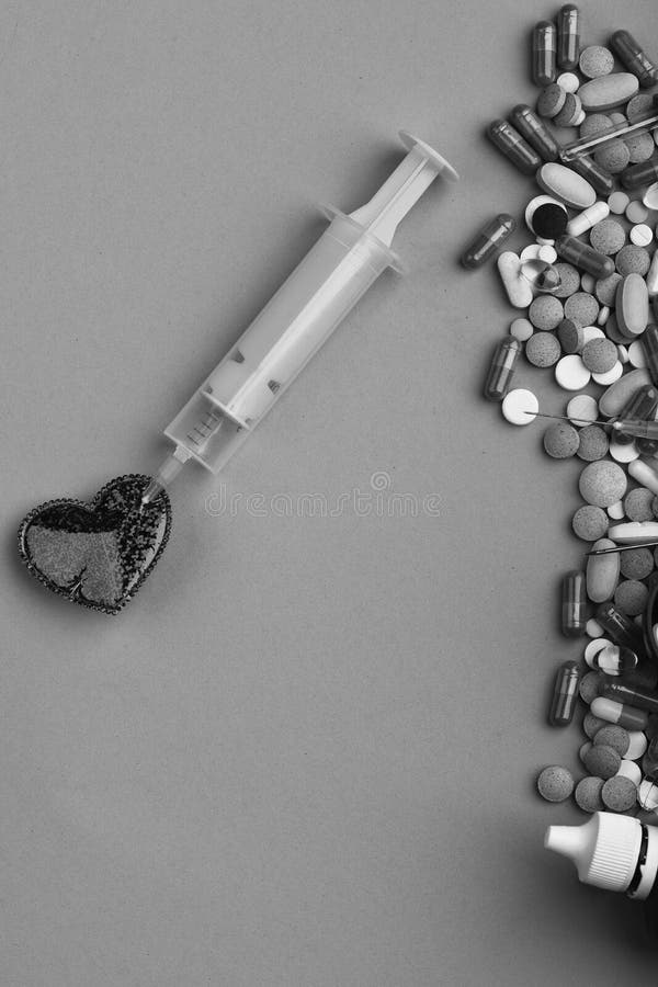 Set of colorful pills scattered on green background, copy space. Frame made of round pills and capsules put in line. Heart disease and medicine concept. Drugs near heart with syringe inside