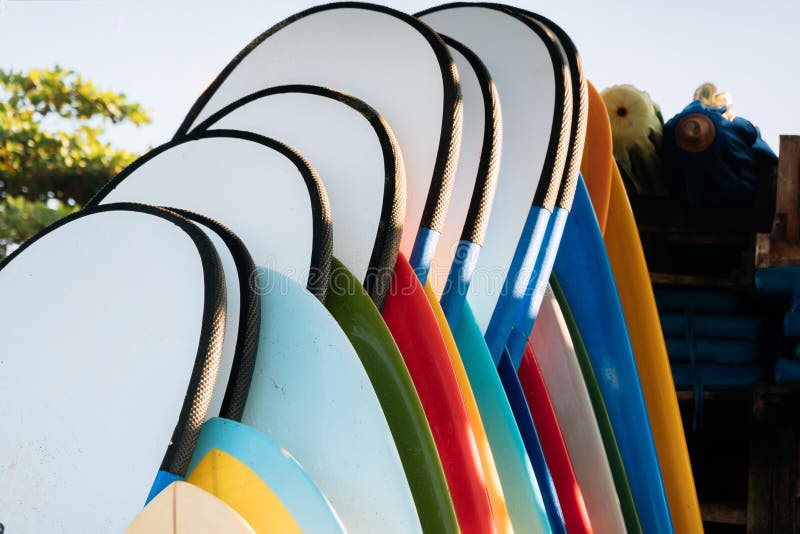 Close Up Set Of Different Color Surf Boards In A Stack On Sandy Beach