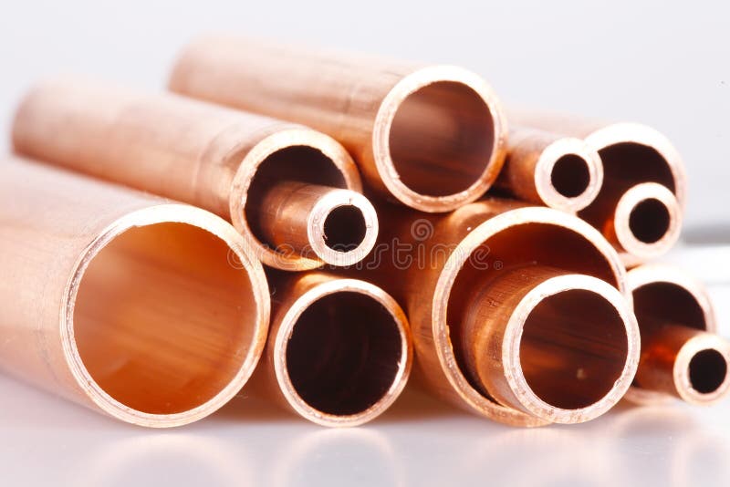 Un conjunto compuesto por cobre tubos de diferente promedio acostada en uno montón.