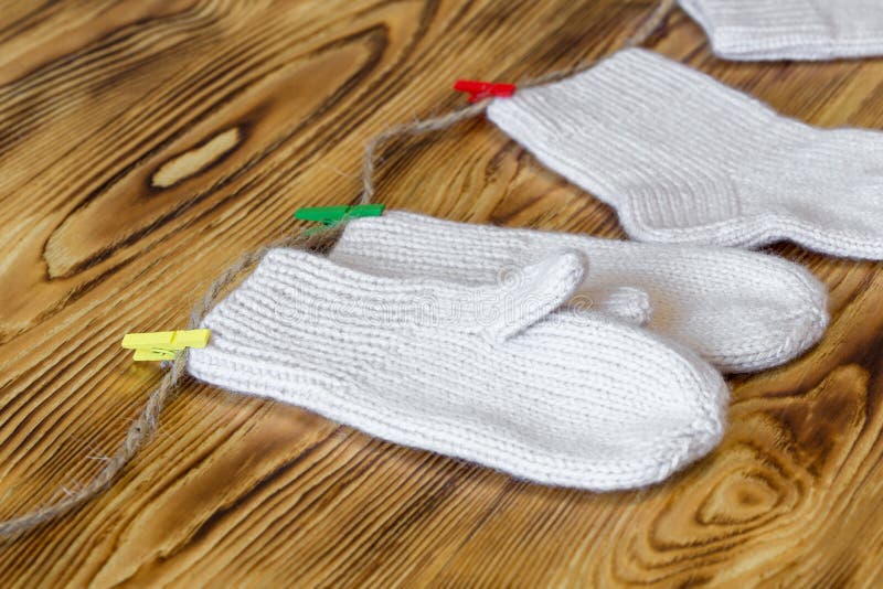 Set of cute knitted cashmere newborn baby socks and gauntlets hanged on pins against wooden background stock photos Set of cute knitted cashmere newborn baby socks and gauntlets hanged on pins against wooden background stock photos