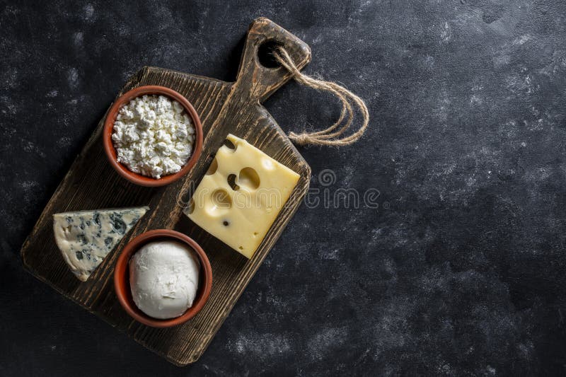 Set di formaggi diversi su tavolette di legno su uno spazio di chiusura in alto di fondo nero. Vari tipi di formaggio fotografia stock libera da diritti