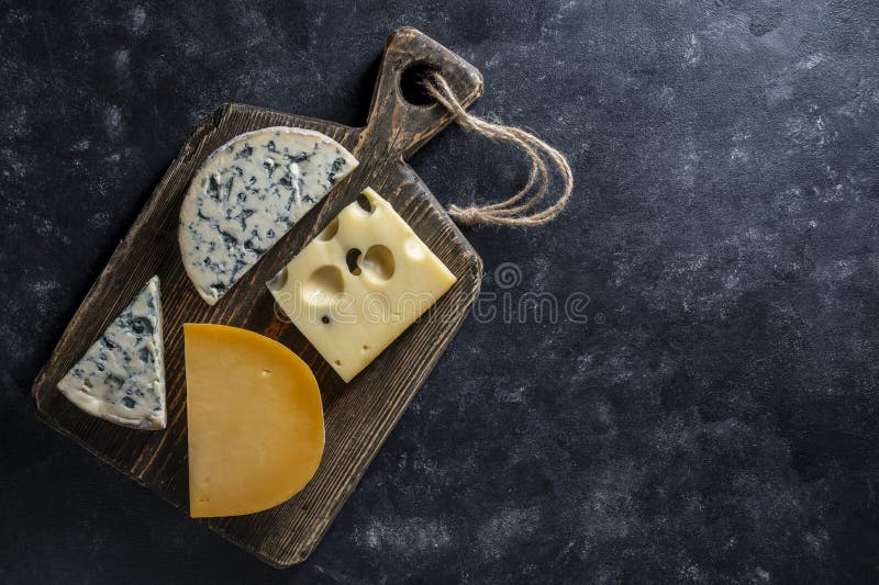 Set di formaggi diversi su tavolette di legno su uno spazio di chiusura in alto di fondo nero. Vari tipi di formaggio fotografia stock