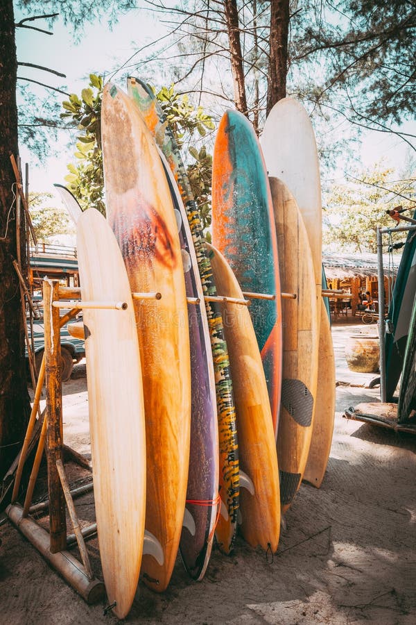 Set of different colorful surf boards in a stack available for rent on the beach. Vertical surfboards, vintage color tone effect