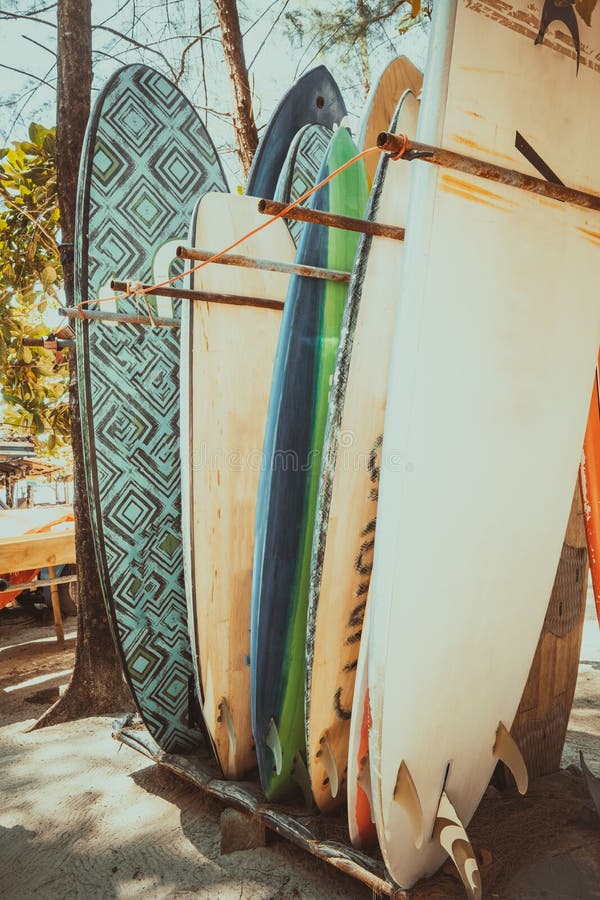 Set of different colorful surf boards in a stack available for rent on the beach. Vertical surfboards, vintage color tone effect