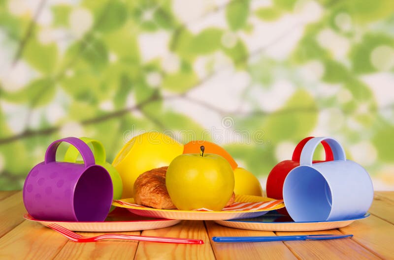 Set of disposable plastic utensils, an apple and croissant in plate, on table royalty free stock photo