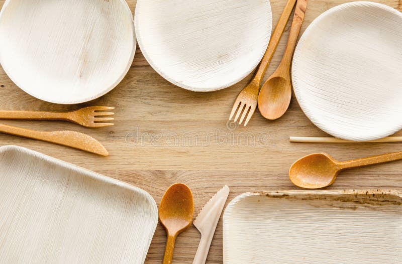 Set of dry biodegradable empty new palm leaf plates and edible fork, knife, spoon and bamboo straw border.