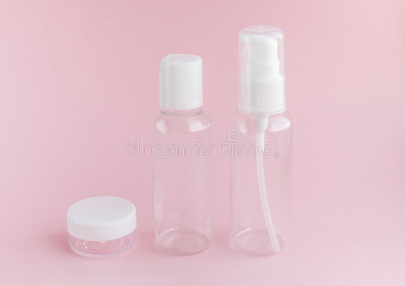Set of empty jars for use on a travel on soft pink background. For all toiletries, shampoo, lotion, nail varnish remover and shower gels. Conception of care of female beauty of the face and body. A small thing which will always be located in a female handbag