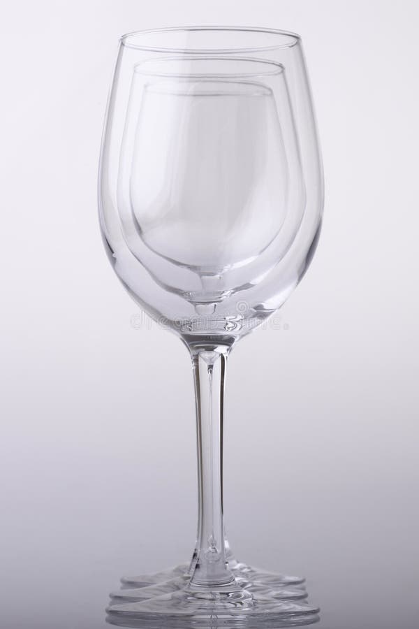 Set of three clean gauzy empty wine glasses standing in a row on light grey background, vertical picture. Set of three clean gauzy empty wine glasses standing in a row on light grey background, vertical picture