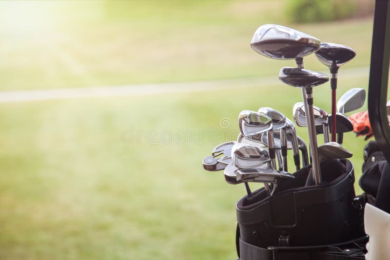 Set of golf clubs over green field background