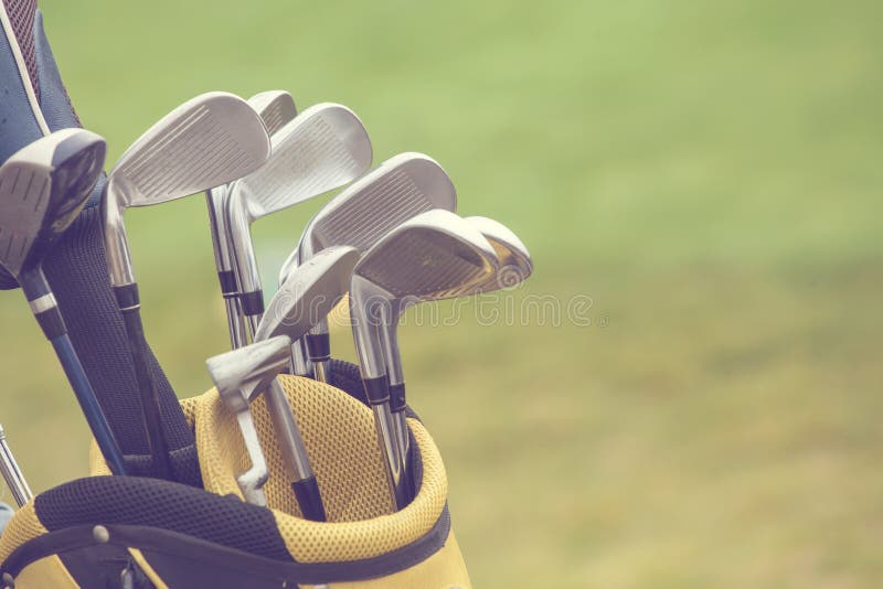 Set of golf clubs over green field