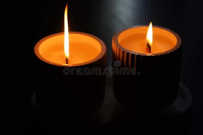 A Set of Lit White Candles Flickering in the Dark on a Black Background