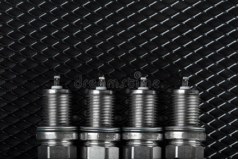 A set of new spark plugs of the car, and spare parts of vehicles on a dark background