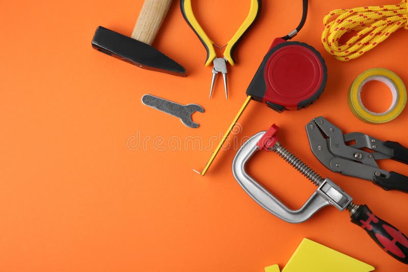 Set of repair tools on orange , flat lay. Space for text