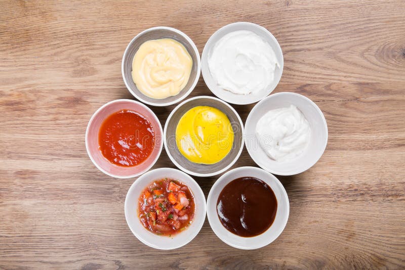 Set of sauces - ketchup, mayonnaise, mustard soy sauce, bbq sauce, mustard grains and pomegranate sauce on wooden table