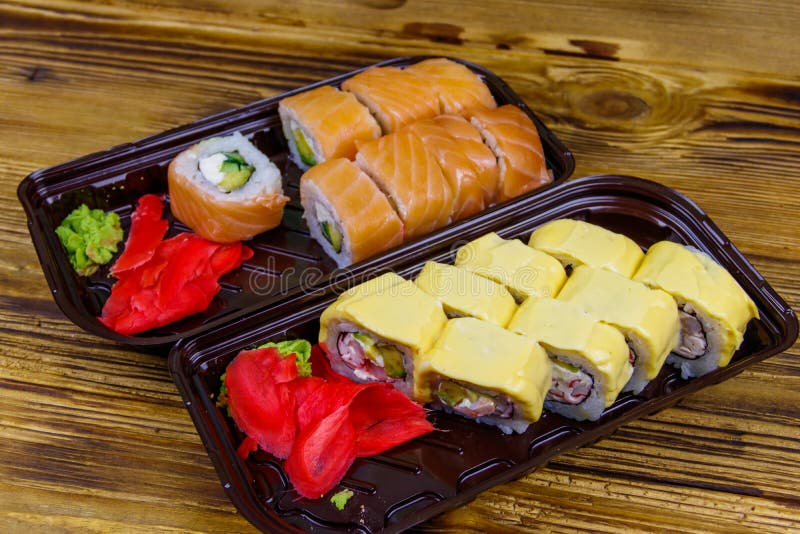 Set of Sushi Rolls in Plastic Boxes on Wooden Table. Sushi for Take
