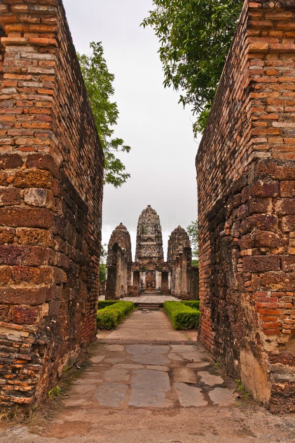 Set of three pagodas behind wall in sukhothai