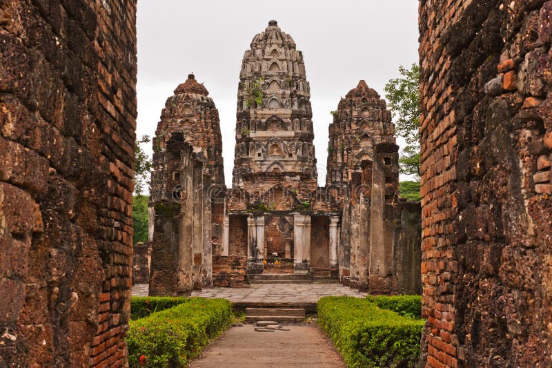 Set of three pagodas behind wall in sukhothai