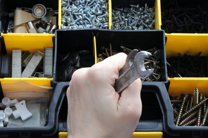 A set of tools in a plastic box, a wrench in his hand.