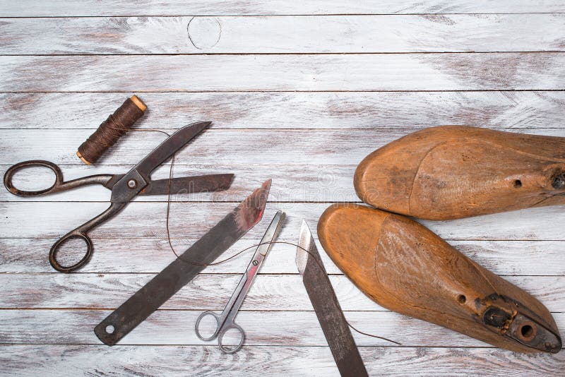 Un conjunto compuesto por herramientas zapatero sobre el blanco de madera.