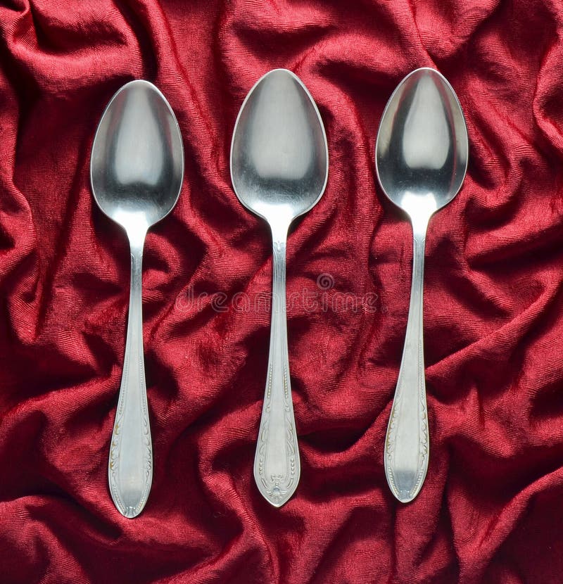 Set trzy metal łyżki na czerwonym jedwabniczym tablecloth fotografia stock Set trzy metal łyżki na czerwonym jedwabniczym tablecloth fotografia stock