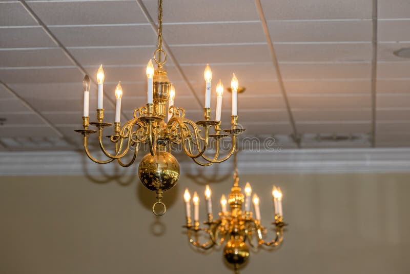 A Set of Two Brass Gold Chandlier Lights Hanging from a Tile Tiled