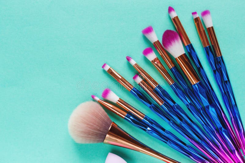 Set of various professional trendy fashion violet purple metallic makeup brushes, beauty blenders on pastel green background stock image Set of various professional trendy fashion violet purple metallic makeup brushes, beauty blenders on pastel green background stock image