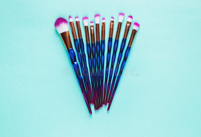 Set of various professional trendy fashion violet purple metallic makeup brushes on pastel green background. Flat lay, top view. royalty free stock image Set of various professional trendy fashion violet purple metallic makeup brushes on pastel green background. Flat lay, top view. royalty free stock image