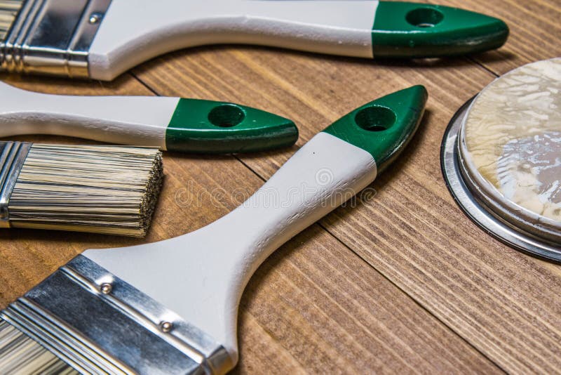 A Set of White Paint Brushes, a Metal Can with White Paint on a Wooden