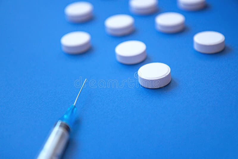 Set of white pills and syringe on blue background. Pills background. White tablets on a blue background