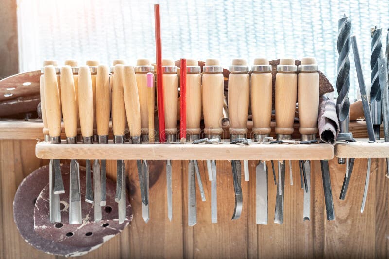 Set of woodworking tools and equipment hanged on wall at carpentry. Different chisels, drills and pencils at craftsman workshop.